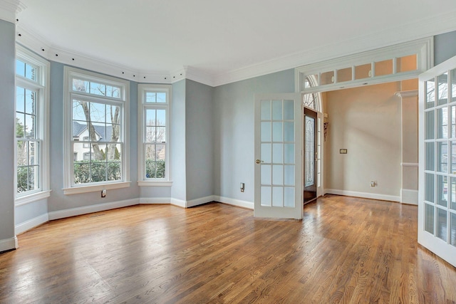 unfurnished room with baseboards, wood finished floors, crown molding, and french doors