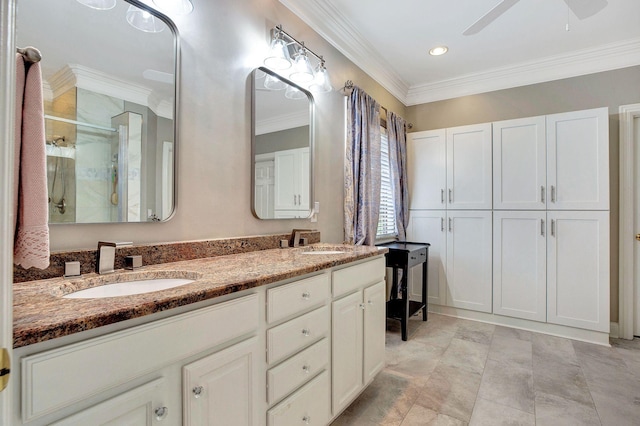 bathroom featuring double vanity, a stall shower, a ceiling fan, ornamental molding, and a sink