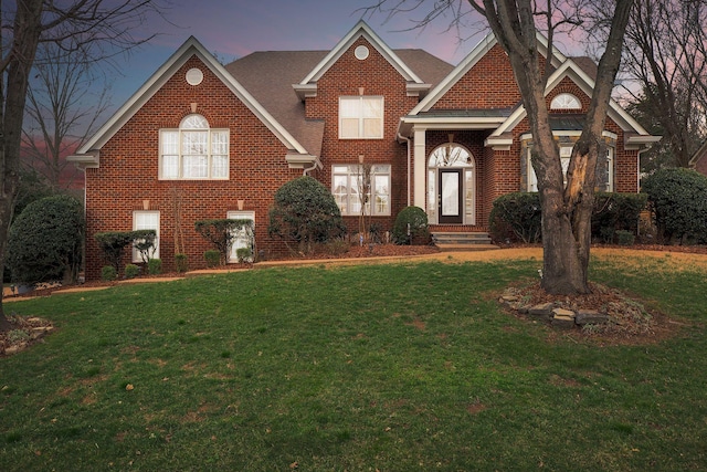 traditional-style home featuring brick siding and a front yard