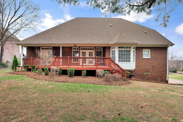 back of house featuring a deck, roof with shingles, brick siding, and a lawn