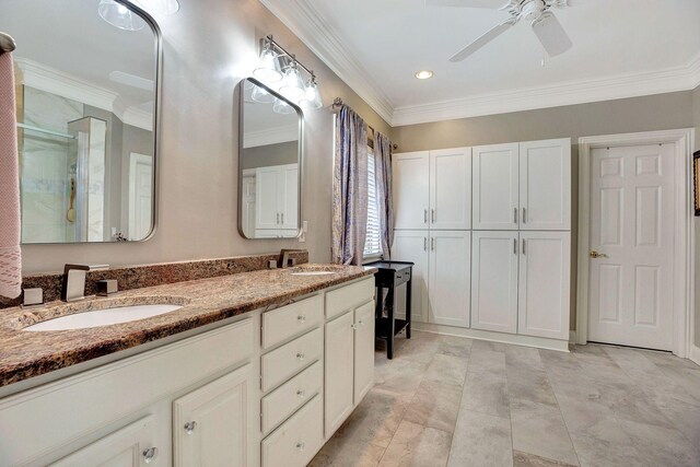 bathroom with double vanity, a sink, a shower with door, and crown molding