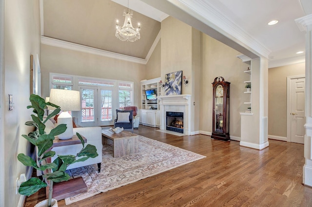 living room with baseboards, a fireplace with flush hearth, wood finished floors, crown molding, and french doors