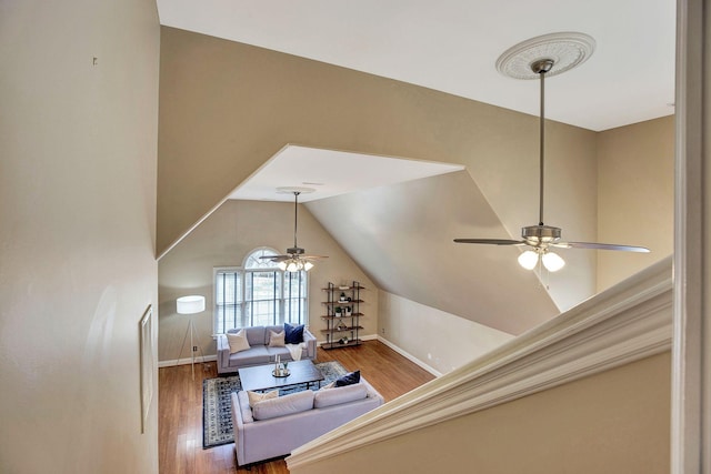 living area with lofted ceiling, ceiling fan, baseboards, and wood finished floors