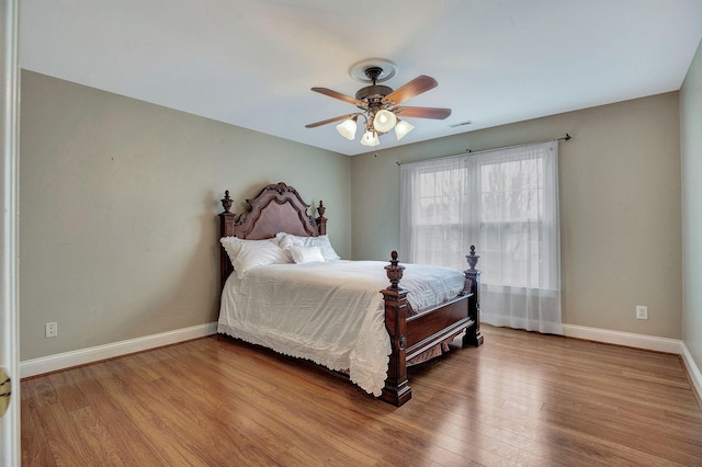 bedroom with ceiling fan, wood finished floors, and baseboards