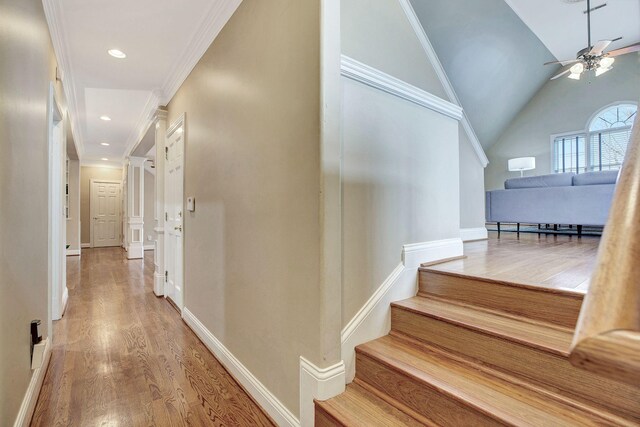 corridor featuring light wood-style flooring, recessed lighting, baseboards, vaulted ceiling, and ornamental molding