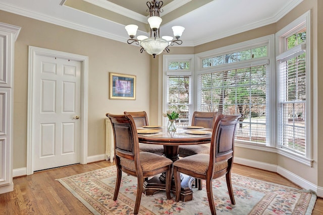 dining room with baseboards, light wood-style floors, a tray ceiling, an inviting chandelier, and crown molding