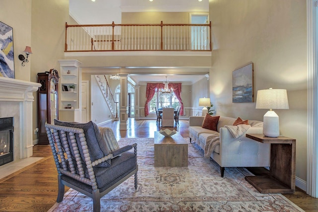 living room with a fireplace with flush hearth, baseboards, wood finished floors, and ornamental molding