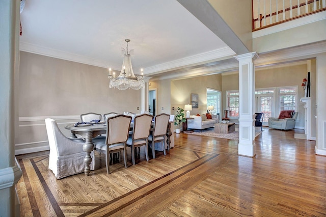 dining room featuring ornate columns, ornamental molding, a notable chandelier, and wood finished floors