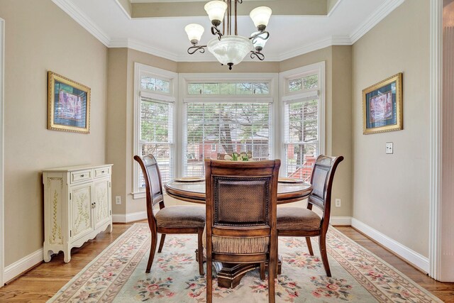 dining area featuring a chandelier, crown molding, light wood-style floors, and baseboards