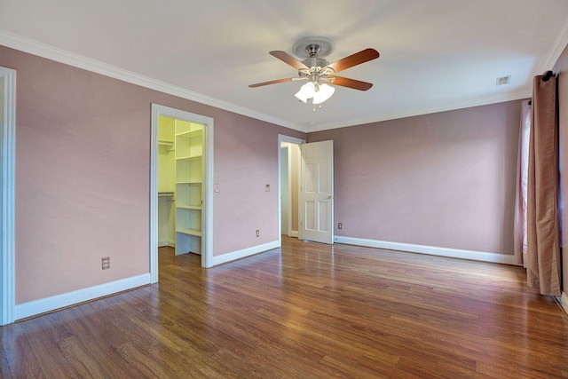 empty room with ceiling fan, wood finished floors, visible vents, baseboards, and ornamental molding