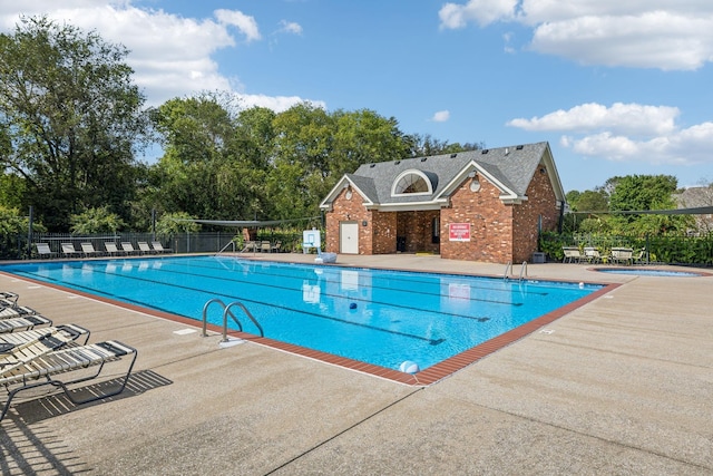 community pool featuring a patio area, a hot tub, and fence