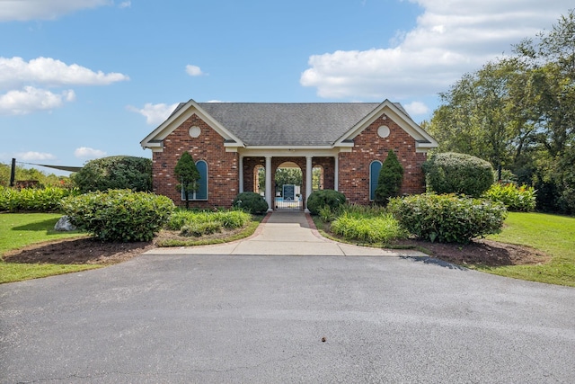 view of front of property featuring a gate, brick siding, and roof with shingles