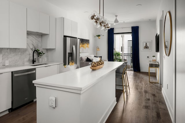 kitchen featuring decorative light fixtures, light countertops, appliances with stainless steel finishes, white cabinetry, and a kitchen island