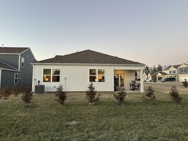 back of house at dusk with a patio, a lawn, and cooling unit