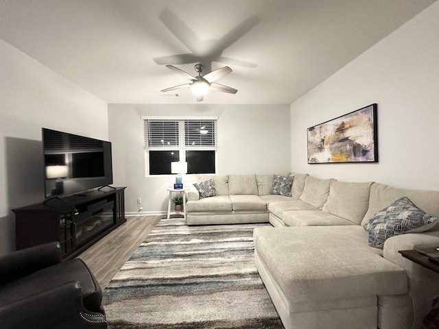 living room with ceiling fan, baseboards, and wood finished floors