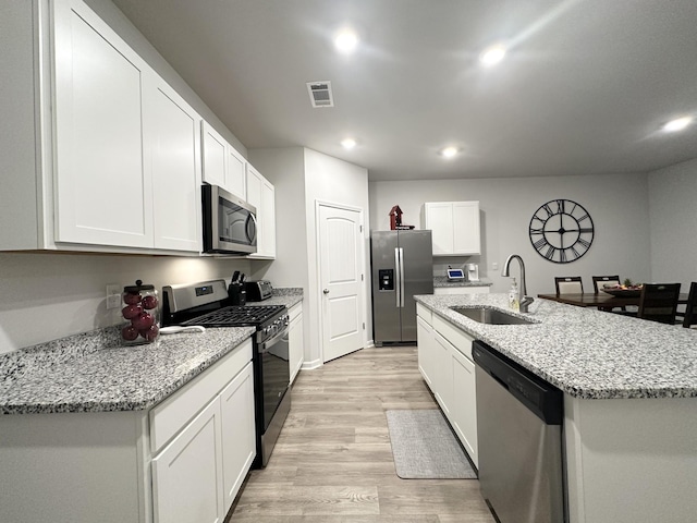 kitchen with a center island with sink, stainless steel appliances, visible vents, white cabinets, and a sink