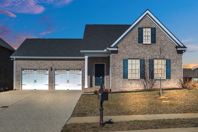 traditional-style house featuring a garage, brick siding, driveway, and a yard