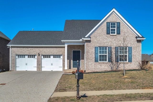 traditional-style home with brick siding, a shingled roof, an attached garage, a front yard, and driveway