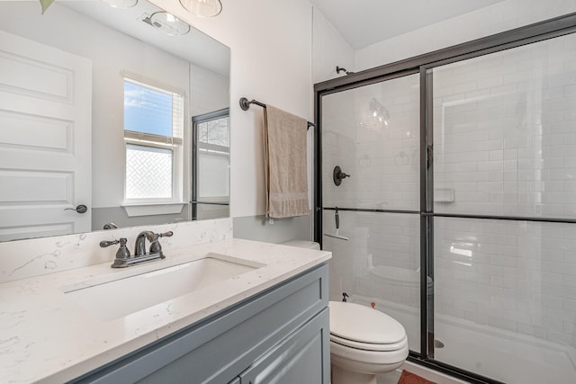 bathroom with a stall shower, vanity, and toilet