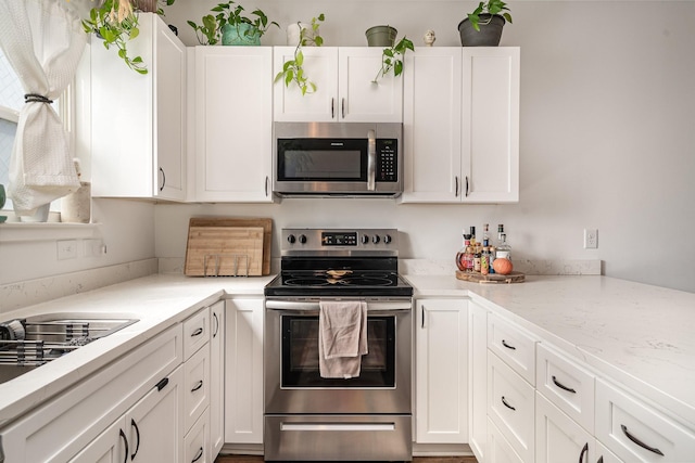 kitchen featuring stainless steel appliances, light stone counters, and white cabinets