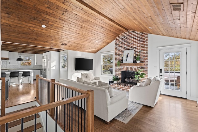 living area featuring visible vents, lofted ceiling, wooden ceiling, wood finished floors, and a brick fireplace