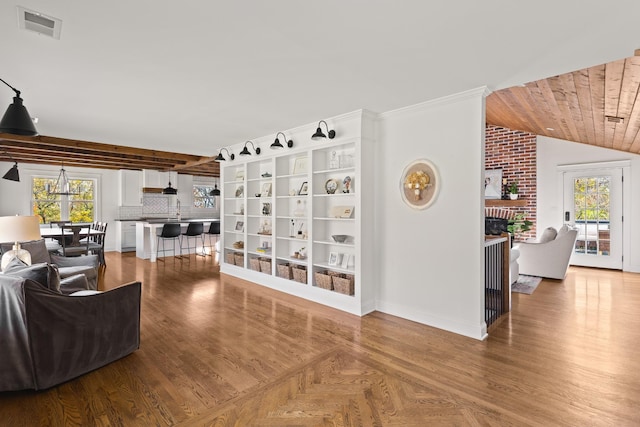 living area with lofted ceiling, a brick fireplace, wood finished floors, and visible vents