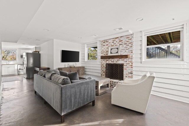 living area with concrete floors, a brick fireplace, and visible vents