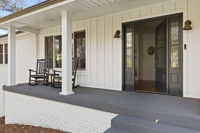 entrance to property with a porch and brick siding