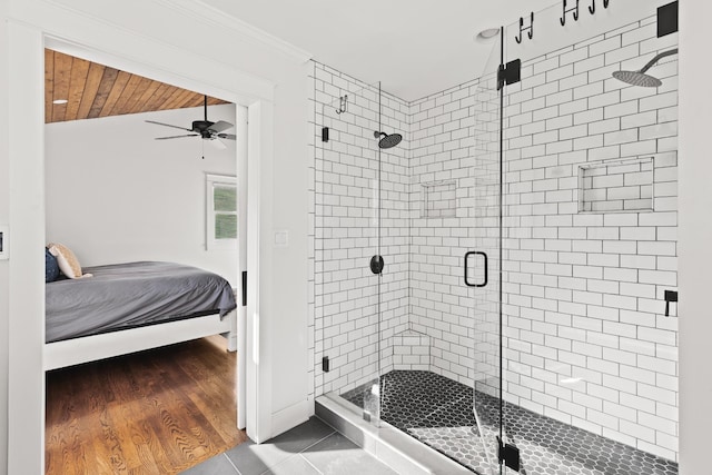 ensuite bathroom with connected bathroom, lofted ceiling, wood finished floors, crown molding, and a shower stall