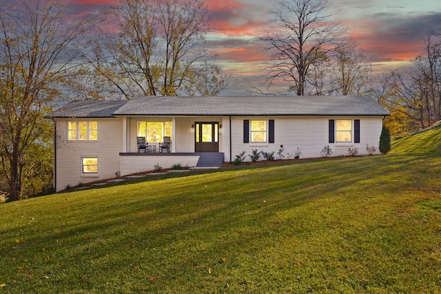 view of front of property with brick siding and a yard