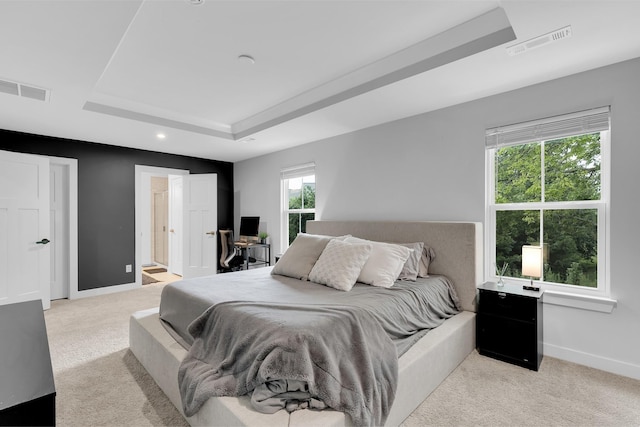 bedroom featuring a tray ceiling, visible vents, light carpet, and baseboards