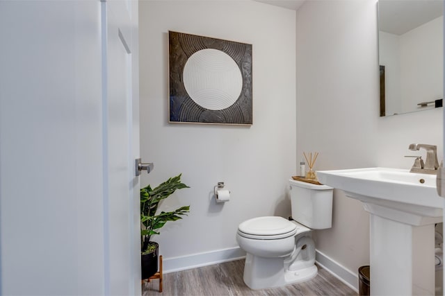 bathroom with baseboards, toilet, and wood finished floors