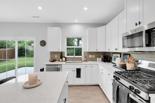 kitchen featuring stainless steel appliances, visible vents, a sink, and white cabinetry