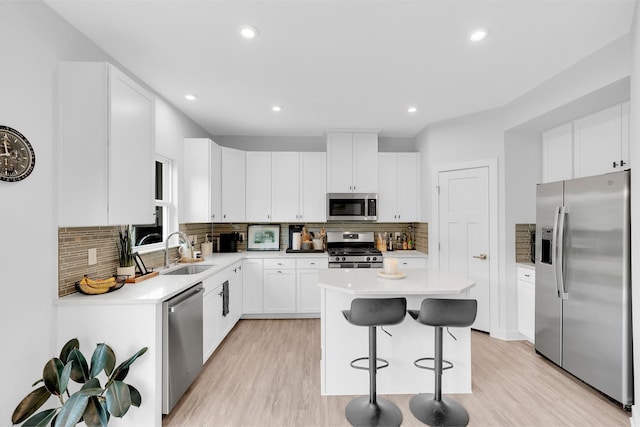 kitchen featuring stainless steel appliances, a center island, light countertops, and a sink