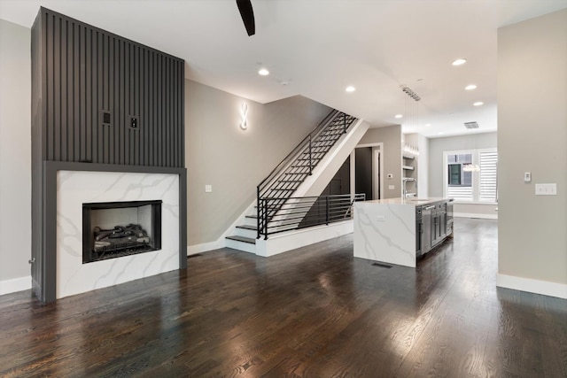 living area featuring recessed lighting, dark wood-type flooring, a fireplace, baseboards, and stairs