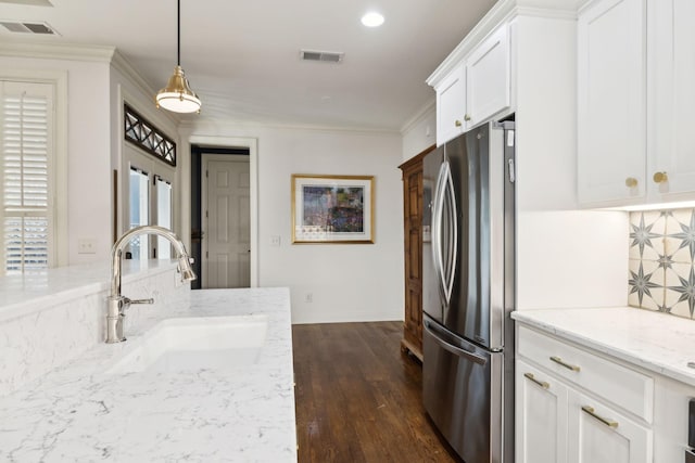 kitchen with visible vents, ornamental molding, freestanding refrigerator, a sink, and backsplash