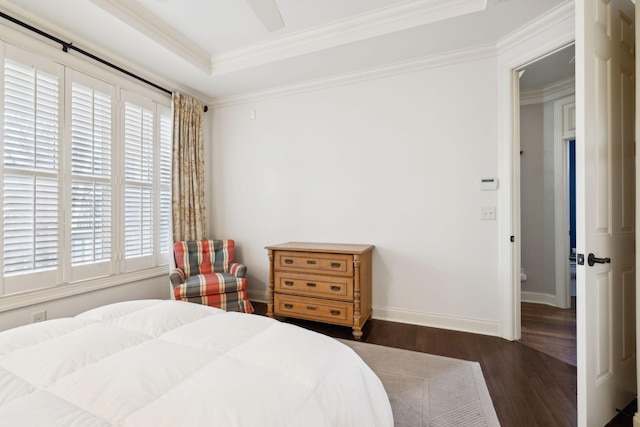 bedroom featuring a tray ceiling, crown molding, a ceiling fan, wood finished floors, and baseboards