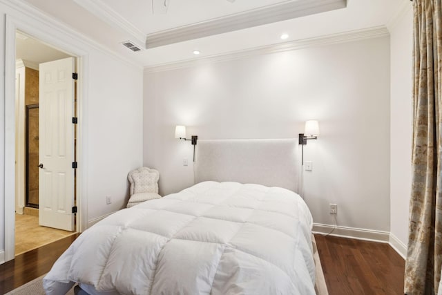 bedroom with crown molding, a tray ceiling, wood finished floors, and baseboards