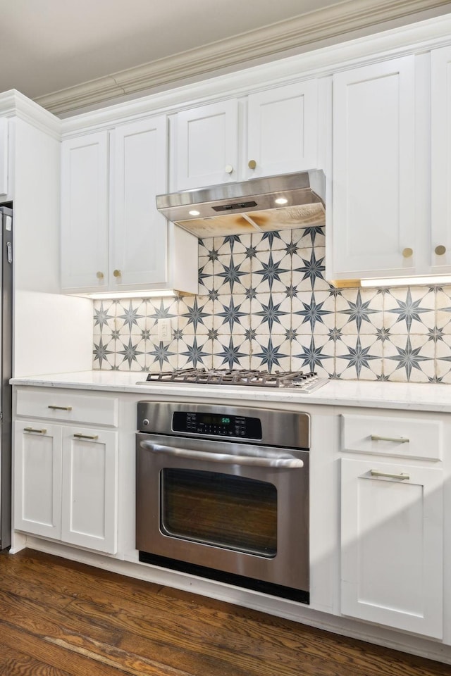 kitchen featuring white cabinets, extractor fan, tasteful backsplash, and stainless steel appliances