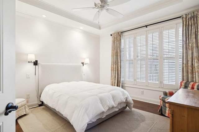 bedroom featuring a raised ceiling, ornamental molding, a ceiling fan, wood finished floors, and baseboards