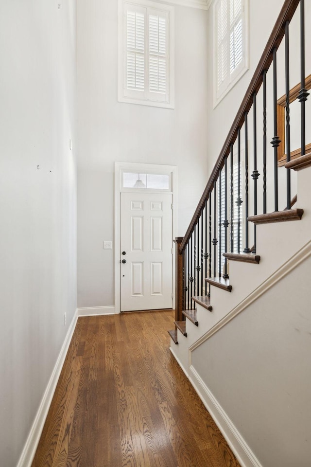 entrance foyer featuring stairs, a high ceiling, wood finished floors, and baseboards