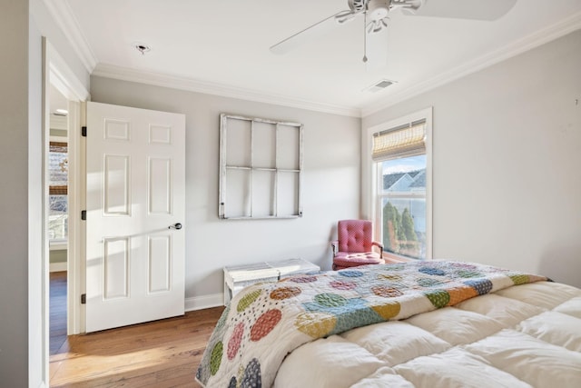 bedroom featuring crown molding, visible vents, ceiling fan, wood finished floors, and baseboards