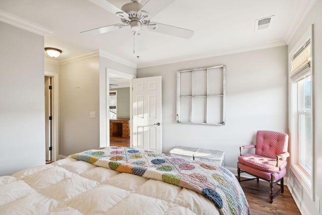 bedroom with baseboards, visible vents, ceiling fan, wood finished floors, and crown molding