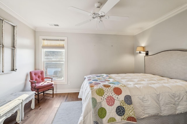 bedroom featuring ornamental molding, light wood-type flooring, visible vents, and baseboards