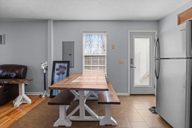 dining space featuring electric panel, a textured ceiling, and baseboards