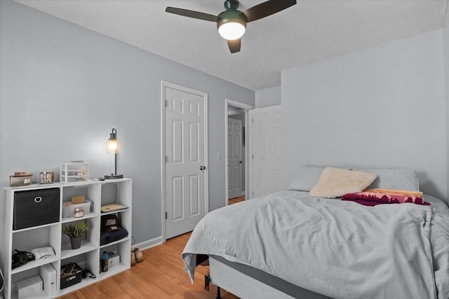 bedroom with light wood-type flooring, a ceiling fan, and baseboards