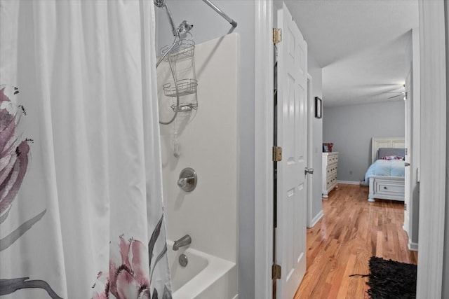 bathroom featuring ensuite bath, baseboards, shower / bath combo with shower curtain, and wood finished floors