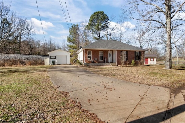 single story home with an outbuilding, covered porch, brick siding, concrete driveway, and a front yard