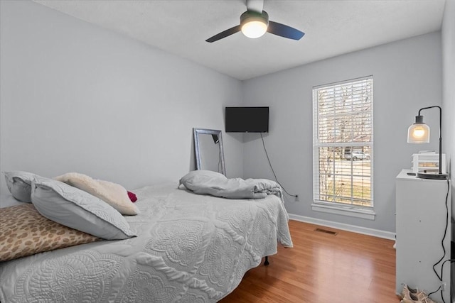 bedroom featuring multiple windows, wood finished floors, visible vents, and baseboards