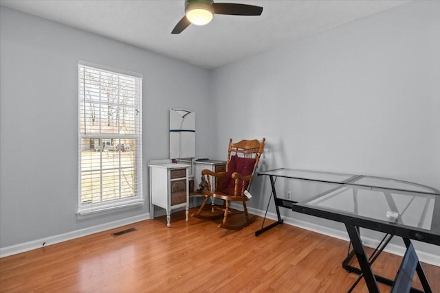 interior space with visible vents, a ceiling fan, light wood-style flooring, and baseboards